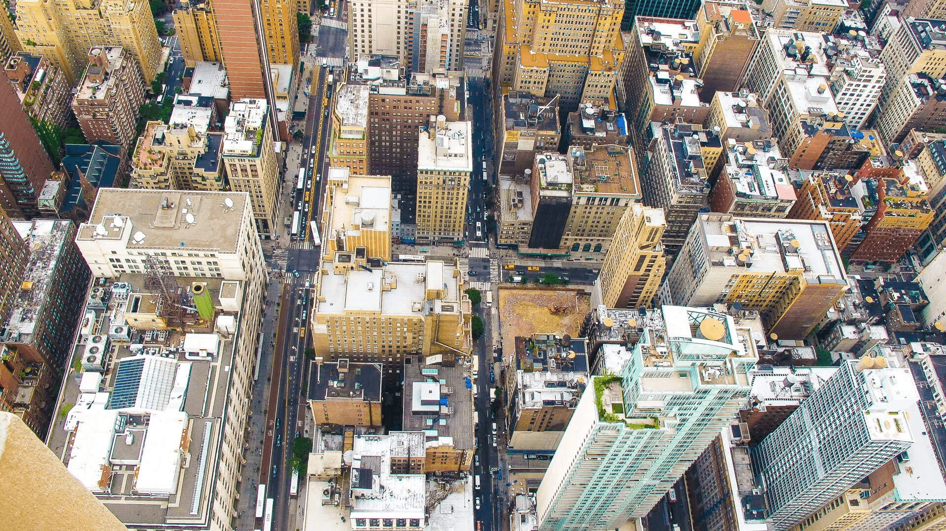 Aerial shot of a bustling cityscape with tall buildings and busy streets, showcasing the density and complexity of urban