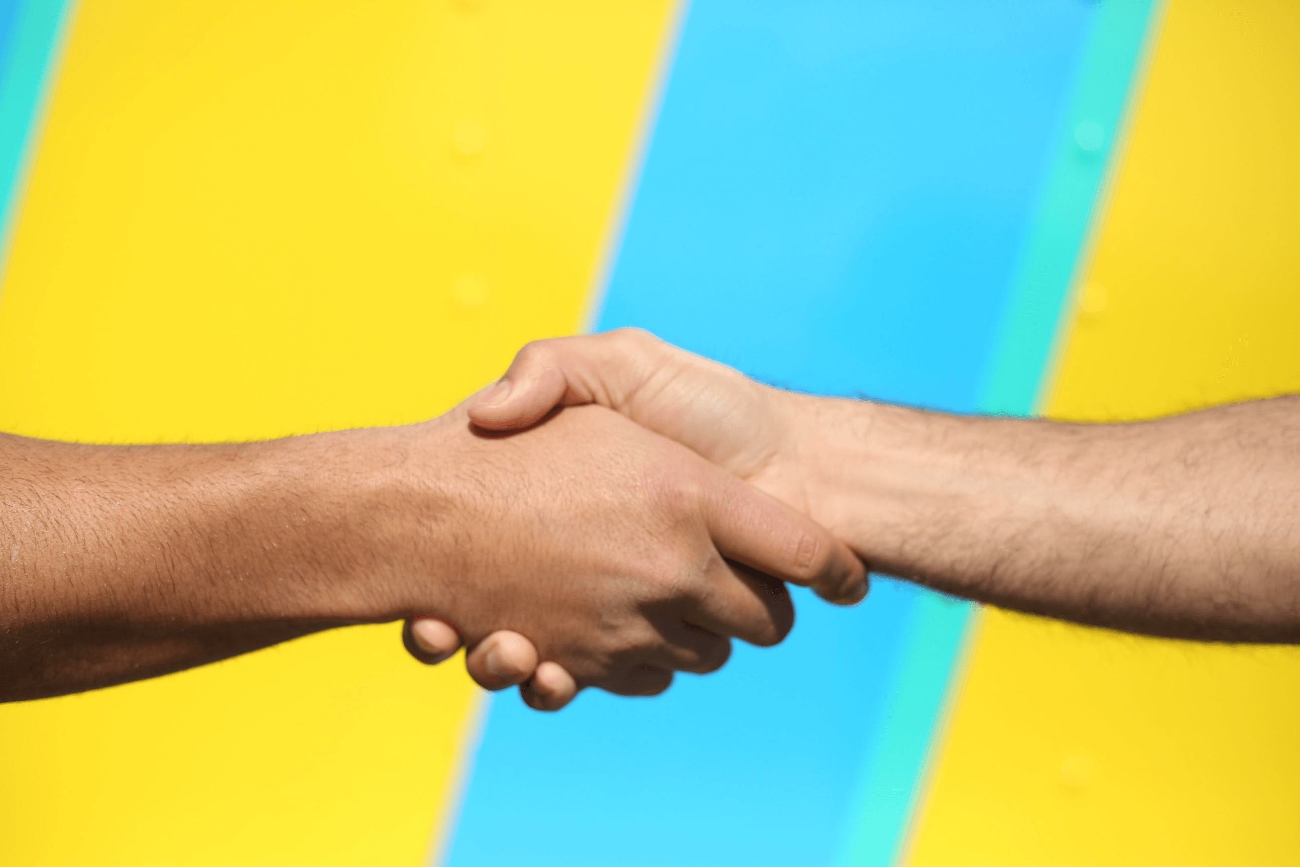 Two hands shaking against a vibrant yellow and blue background, symbolizing partnership and collaboration.