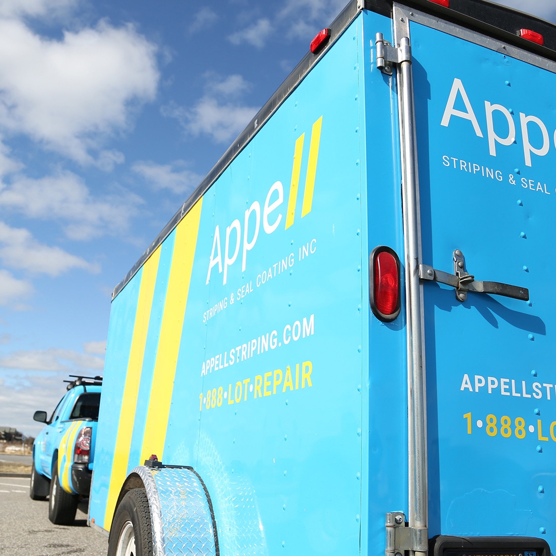 A blue and yellow Appell Striping & Seal Coating Inc. truck parked under a clear sky.