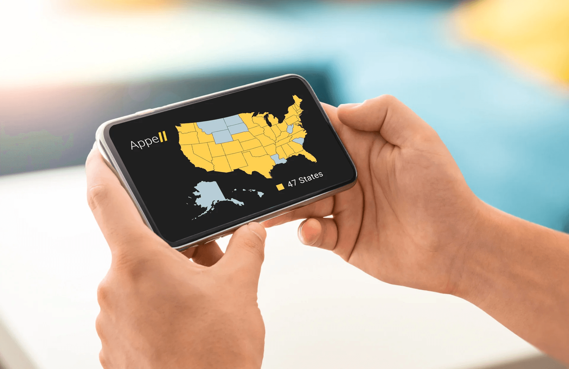 Hands holding a smartphone displaying a map of the United States with 47 states highlighted in yellow.